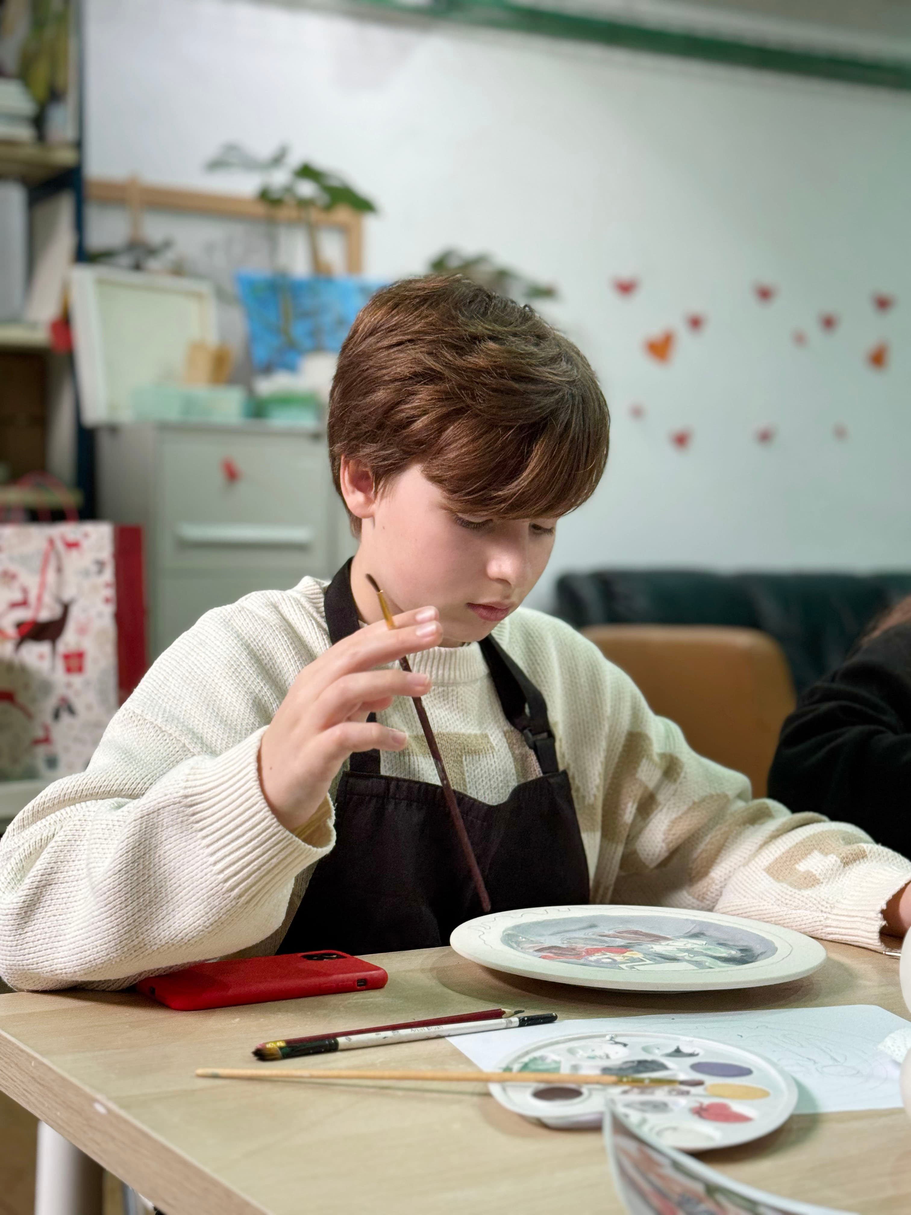 Child painting a ceramic plate